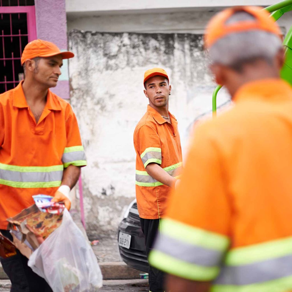 Three junk removal experts, young and old, having a discussion while they clean up.