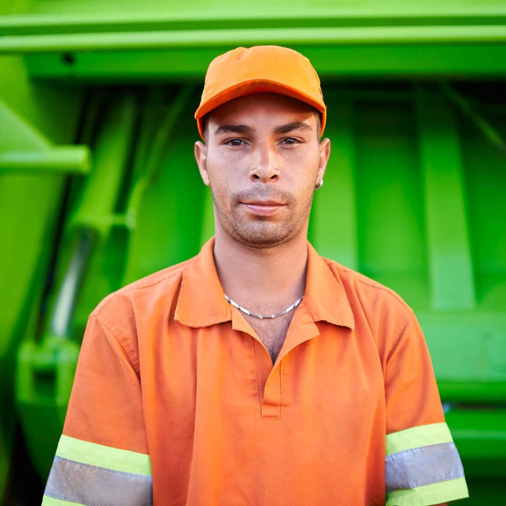 Close up of a trash removal expert in front of a lime green garbage truck.