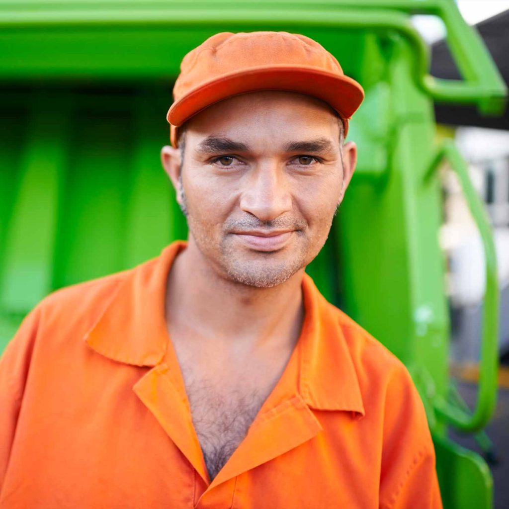 Close up of a trash removal expert in front of a lime green garbage truck.