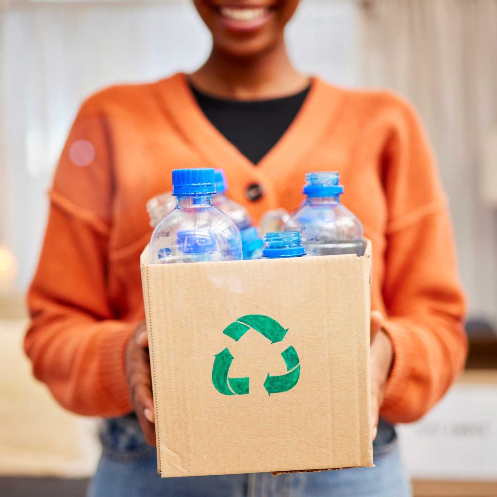 Woman holding a recycle box filled with plastic bottles.
